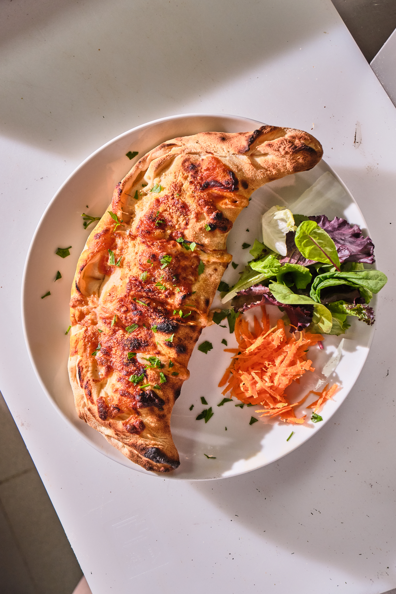 Calzone artesano recién horneado con ensalada al lado